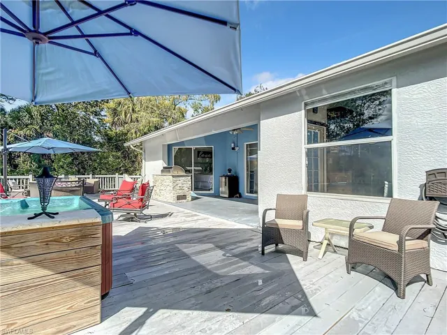 Wooden deck with area for grilling, a hot tub, and a ceiling fan