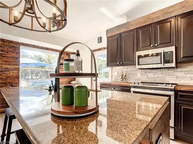 Kitchen featuring dark brown cabinetry, stainless steel appliances, vaulted ceiling, backsplash, and plenty of natural light