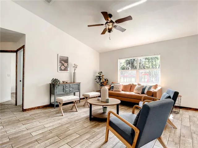 Living room with lofted ceiling, wood finish floors, and a ceiling fan