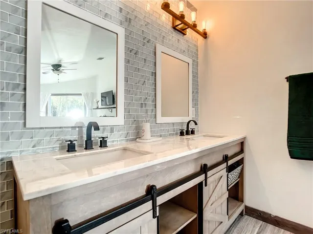 Bathroom with double vanity, backsplash, and ceiling fan