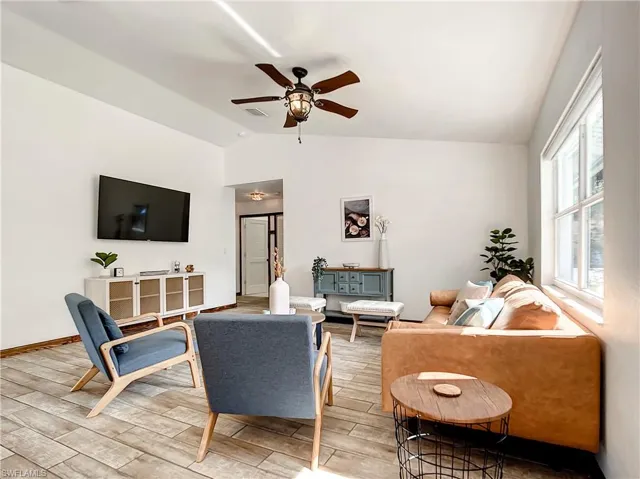 Living room with wood finish floors, lofted ceiling, and a ceiling fan