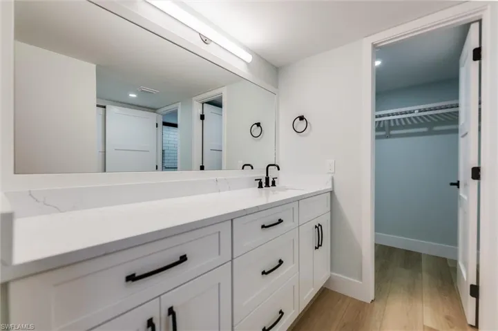 Bathroom featuring a walk in closet, vanity, light wood-type flooring, and recessed lighting
