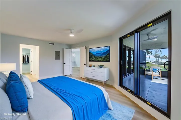 Bedroom featuring access to outside, light wood-style floors, ceiling fan, a walk in closet, and electric panel