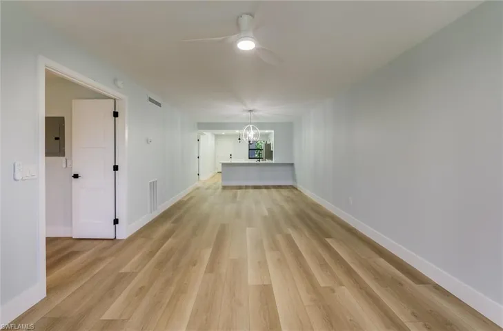 Unfurnished room with ceiling fan, light wood-style flooring, a chandelier, and electric panel