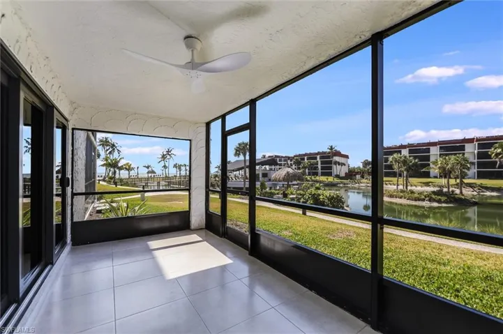 Unfurnished sunroom featuring a ceiling fan and a water view