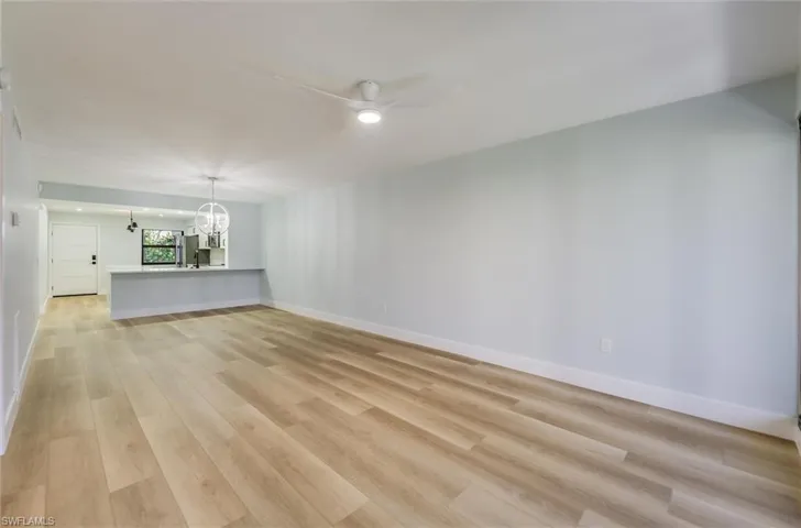Unfurnished living room with a chandelier, ceiling fan, and light wood-style floors