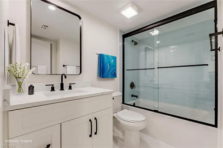 Full bath with vanity and combined bath / shower with glass door