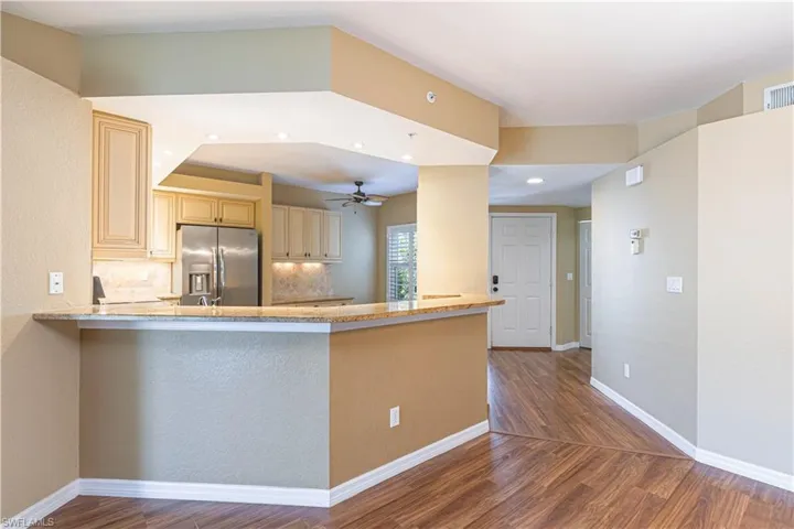 Kitchen featuring cream cabinets, wood finished floors, stainless steel fridge, ceiling fan, and recessed lighting