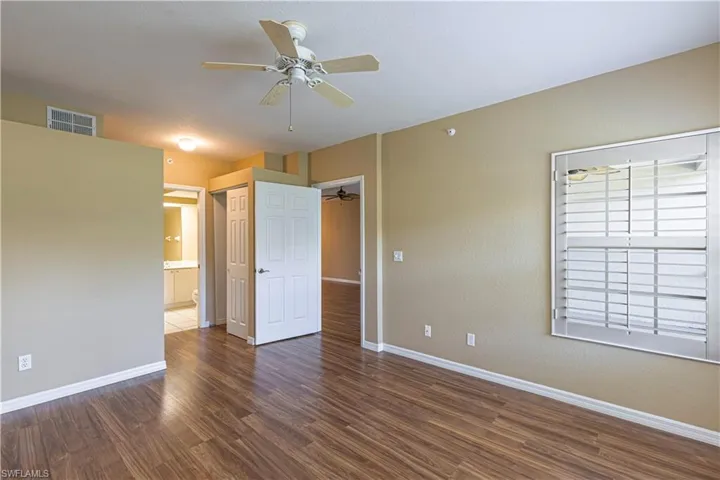 Unfurnished bedroom with wood finished floors, connected bathroom, and ceiling fan