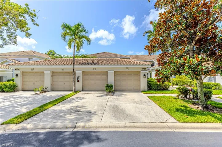 View of front of home featuring stucco siding, community garages, and a tiled roof