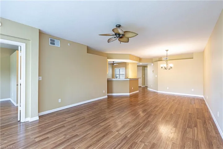 Unfurnished living room with ceiling fan, a chandelier, and wood finished floors