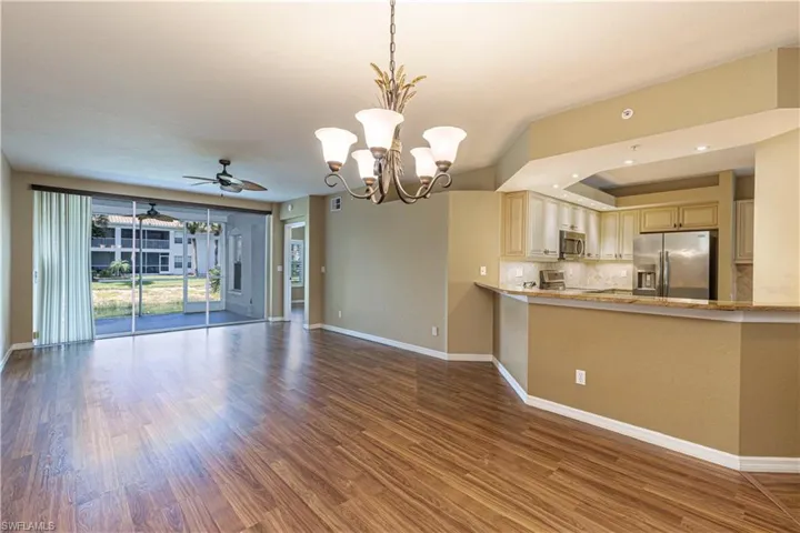 Unfurnished living room with a chandelier, wood finished floors, ceiling fan, and a tray ceiling
