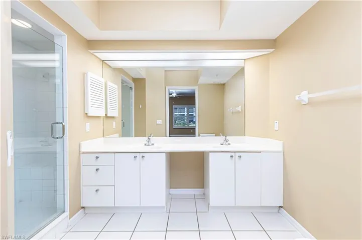 Full bath featuring double vanity, a shower stall, tile patterned flooring, and a ceiling fan