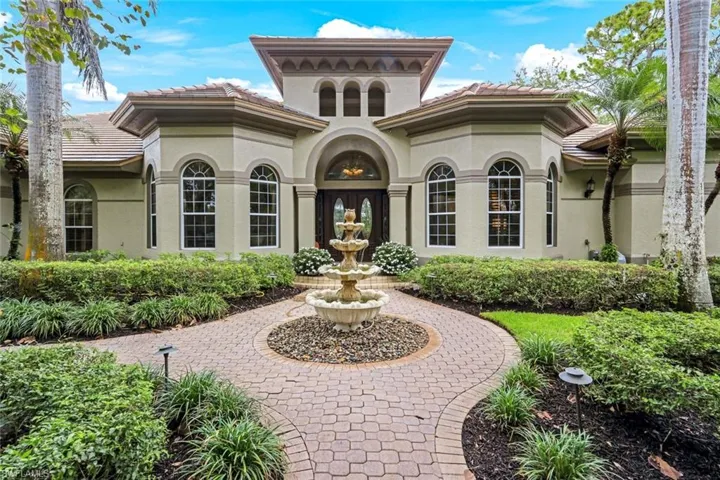 View of the front of the home with fountain and lush landscaping.