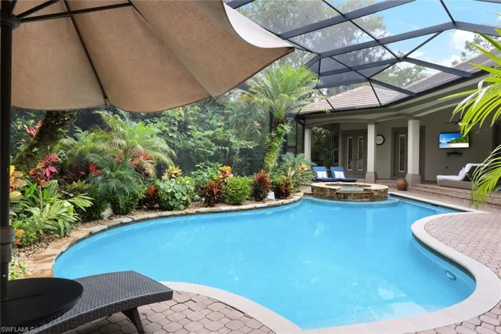 Lush, tropical landscaping frame this gorgeous pool and hot tub.