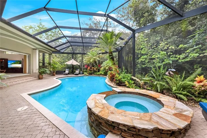 Lush, tropical landscaping frame this gorgeous pool and hot tub.