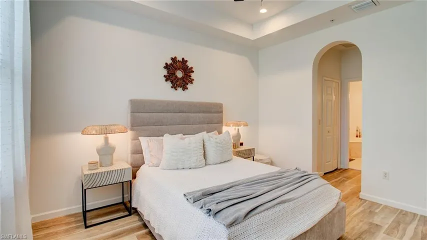 Bedroom featuring arched walkways, light wood-style floors, ensuite bathroom, and recessed lighting