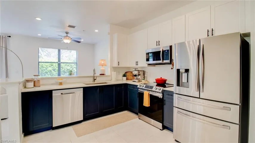 Two tone kitchen with stainless steel appliances, two tone color scheme, recessed lighting, a ceiling fan, and a peninsula