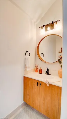 Bathroom featuring vanity, vaulted ceiling, and light tile patterned floors