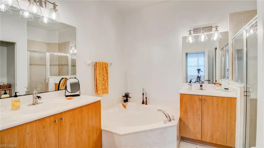 Full bath featuring two vanities, a garden tub, and a stall shower