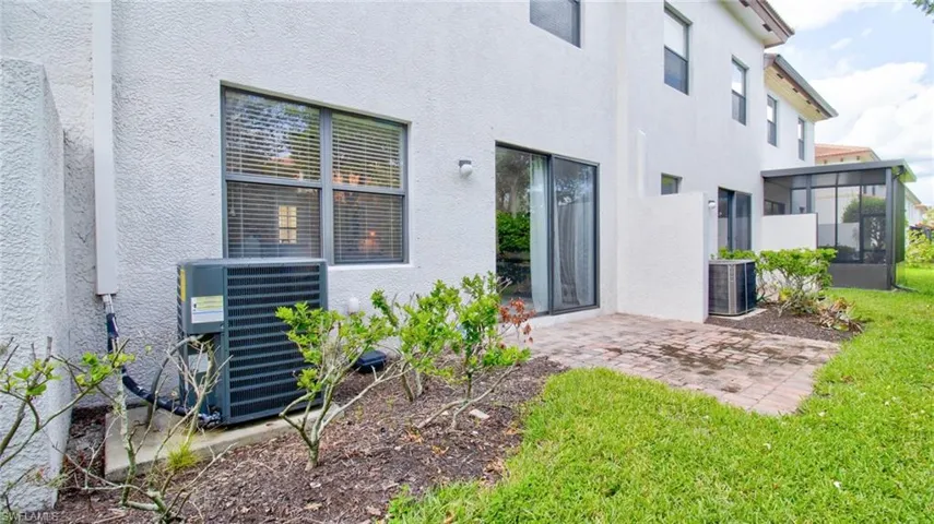 Rear view of property featuring a patio, stucco siding, a sunroom, and a lawn