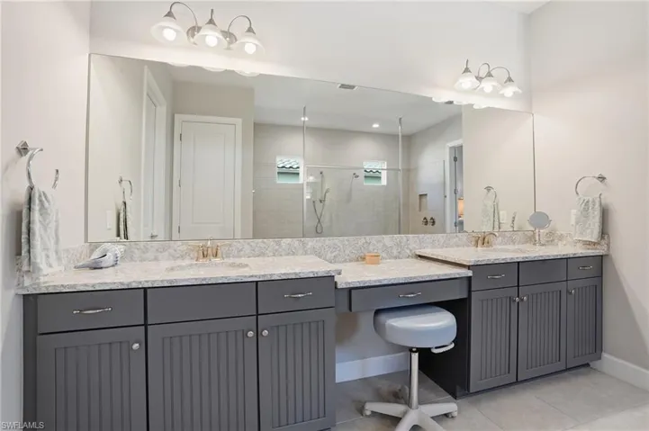 Full bathroom with two vanities, light tile patterned floors, and a shower stall