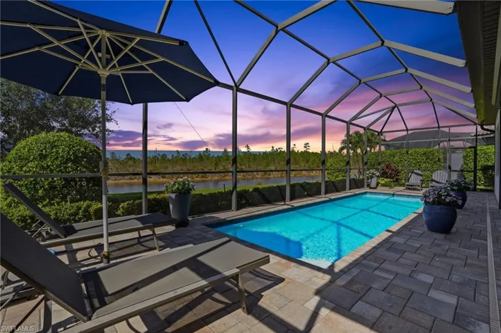 Outdoor pool with a sunroom, a lanai, a patio, and a water view