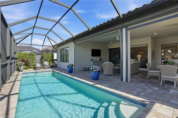 Outdoor pool featuring a patio area, glass enclosure, and a sunroom