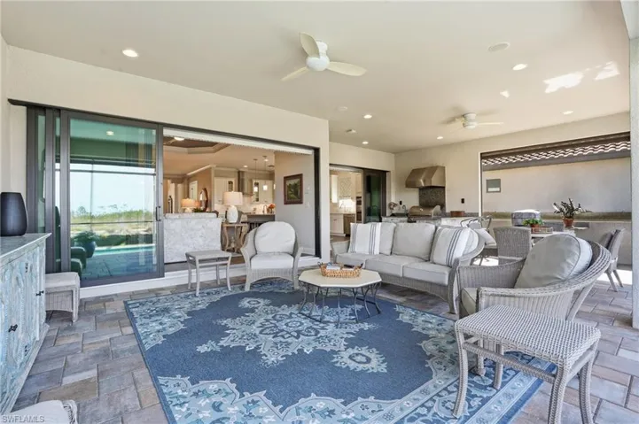 Living room with stone tile flooring, ceiling fan, and recessed lighting
