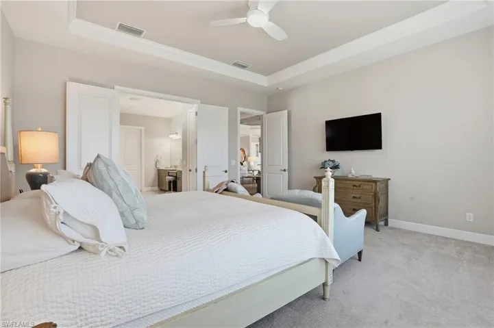 Bedroom with carpet floors, ceiling fan, a tray ceiling, and crown molding