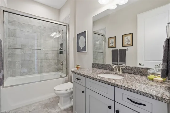 Bathroom featuring vanity and bath / shower combo with glass door