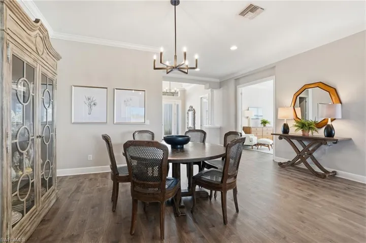 Dining area with crown molding, wood finished floors, and recessed lighting