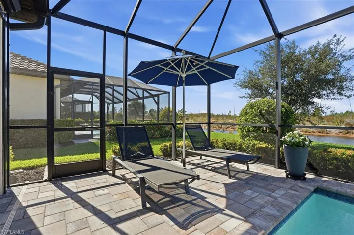 Outdoor pool featuring a lanai, a sunroom, a water view, and a patio area