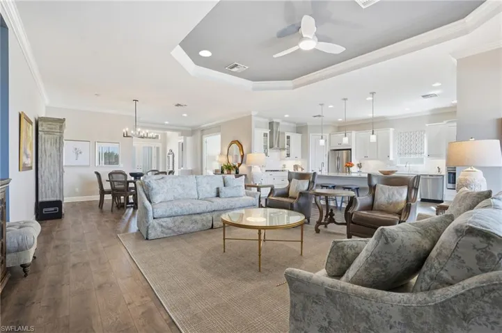 Living room with a ceiling fan, recessed lighting, wood-type flooring, crown molding, and a chandelier
