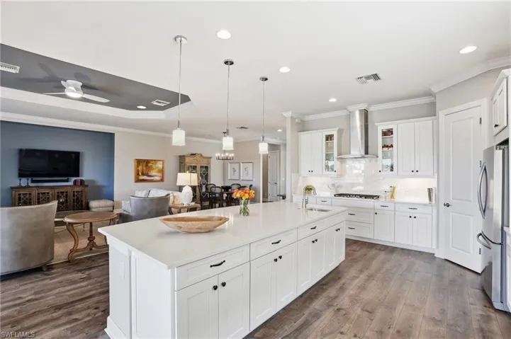 Kitchen with crown molding, hanging light fixtures, white cabinetry, open floor plan, and recessed lighting