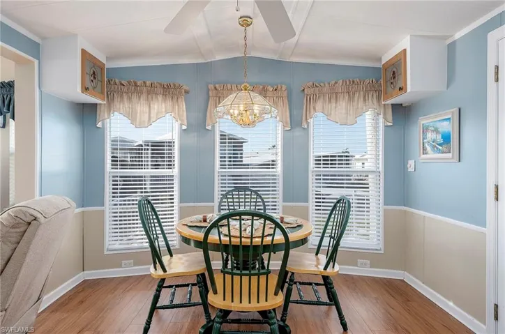 Dining room featuring wood finished floors, ceiling fan with notable chandelier, lofted ceiling, and a healthy amount of sunlight