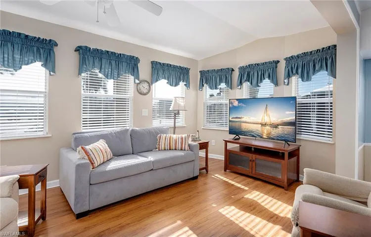 Living room with a ceiling fan, baseboards, wood finished floors, and lofted ceiling