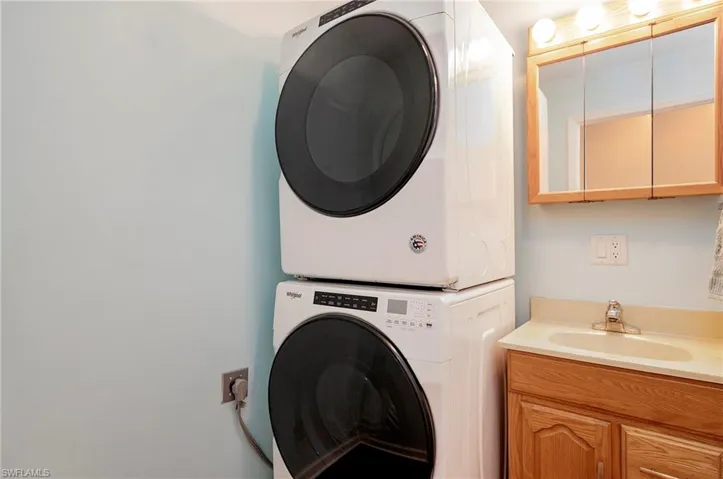Clothes washing area with a sink and stacked washer and clothes dryer