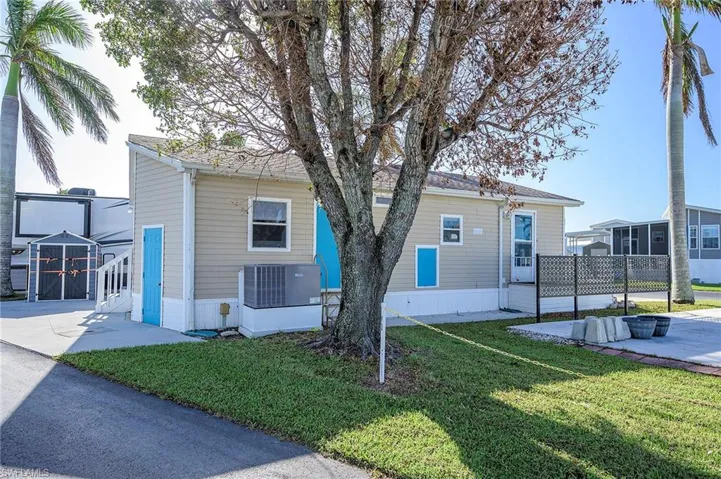 View of front of home with central AC, a front yard, and fence