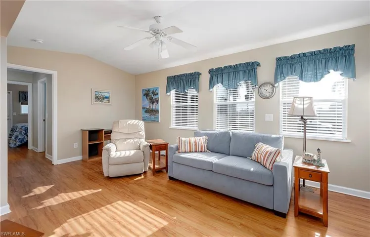 Living area featuring light wood-type flooring, baseboards, ceiling fan, and lofted ceiling