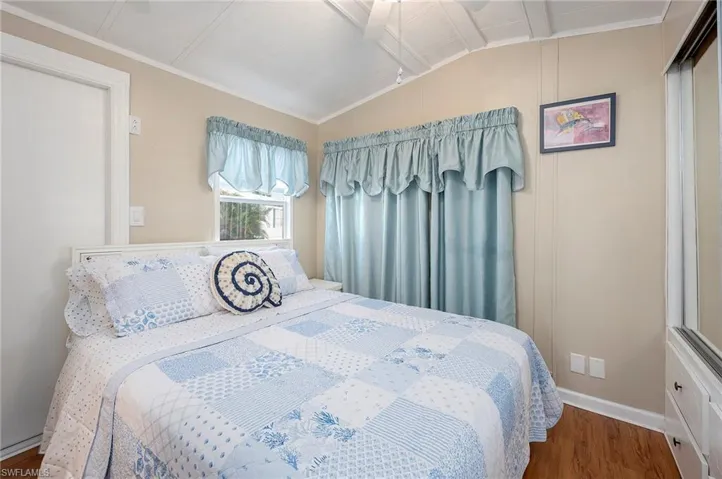 Bedroom featuring baseboards, wood finished floors, and lofted ceiling