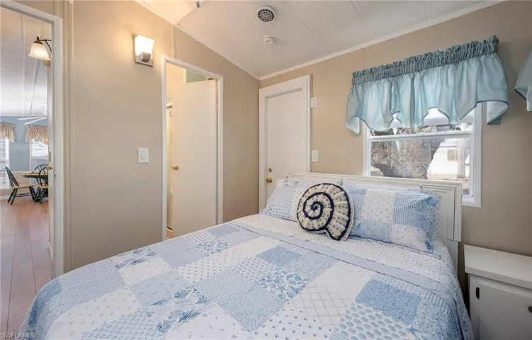 Bedroom featuring multiple windows, ornamental molding, and wood finished floors