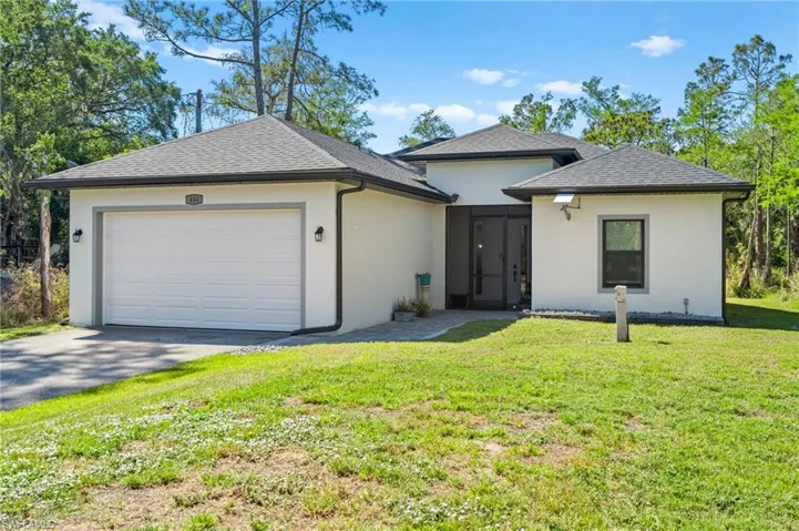 View of front of house with driveway, a garage, a front yard, roof with shingles, and stucco siding