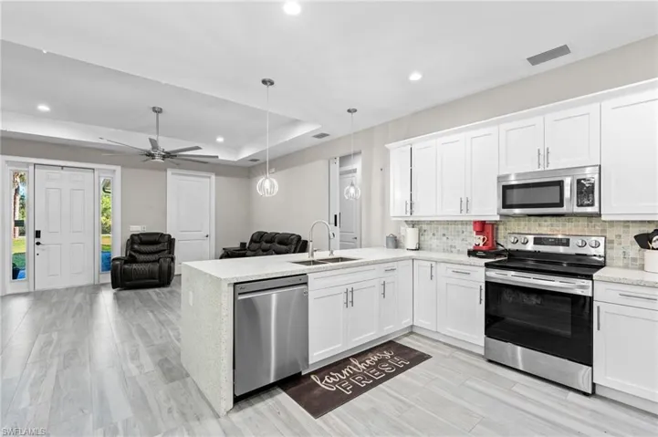 Kitchen featuring open floor plan, a sink, visible vents, a peninsula, and appliances with stainless steel finishes