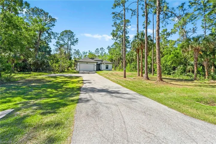 View of front of property featuring driveway, an attached garage, and a front lawn