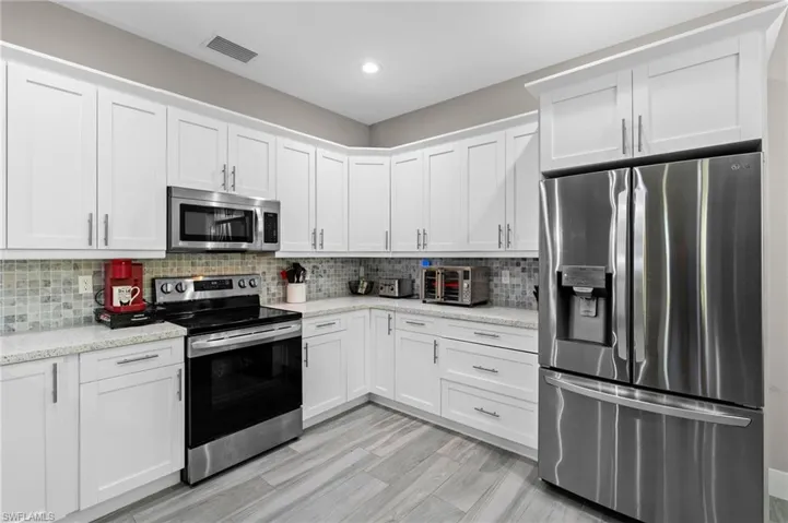 Kitchen with white cabinets, visible vents, tasteful backsplash, and appliances with stainless steel finishes