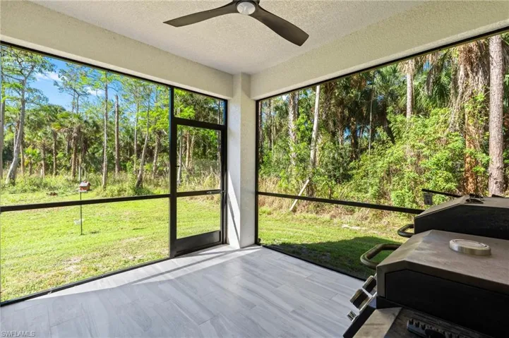 Unfurnished sunroom with a ceiling fan and a forest view