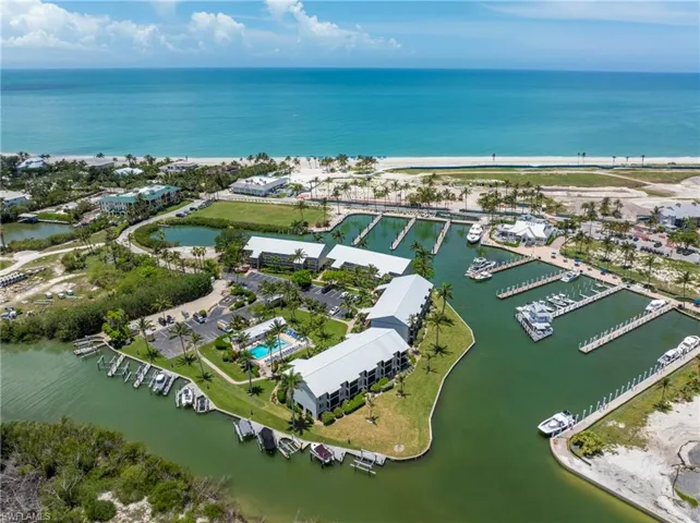 Coastal property featuring multiple marina slips, direct Gulf access, residential buildings with metal roofing, a swimming pool, and proximity to a white sand beach