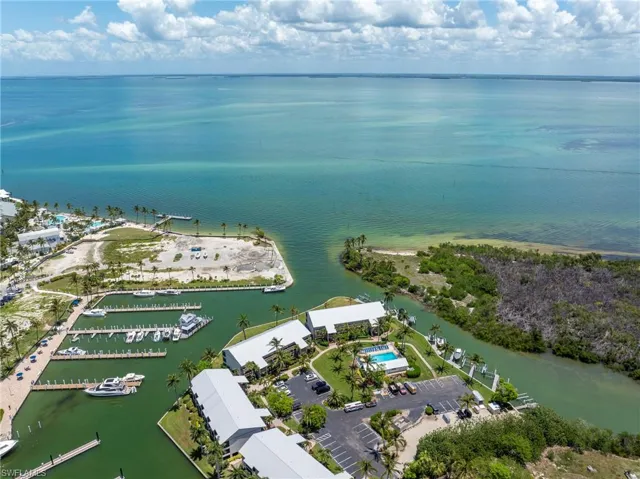 Waterfront property featuring multiple boat docks, direct water access, mature palm trees, a swimming pool, and dedicated parking areas
