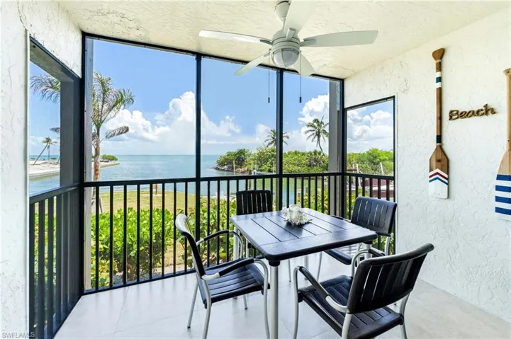 Screened outdoor space featuring water views, a ceiling fan, and white tile flooring